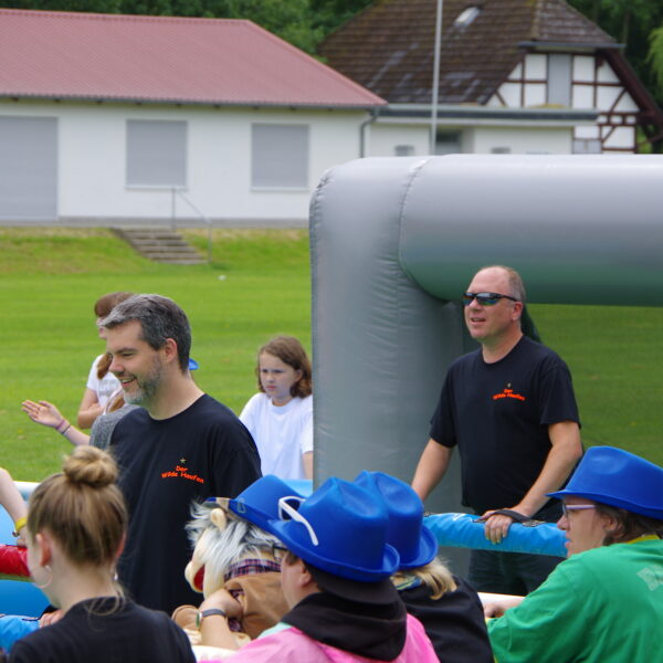 Menschenkicker Cup. Zu sehen ist das Spielfeld mit Spielern. Zuschauer schauen zu.